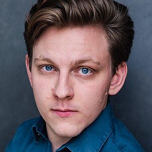 Portraitfoto von Johannes Osenberg. Er hat sein dunkelblondes Haar seitlich zurechtgestylt. Er trägt ein blaues Hemd.