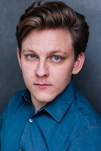 Portraitfoto von Johannes Osenberg. Er hat sein dunkelblondes Haar seitlich zurechtgestylt. Er trägt ein blaues Hemd.