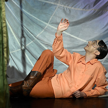 Ein Mann in Orange liegt auf dem Boden. Er schaut nach oben.