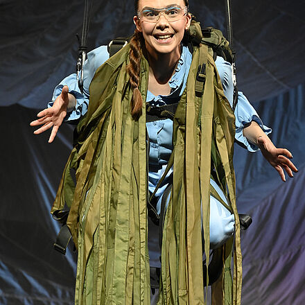 Eine Frau hängt an einer Schaukel auf der Bühne