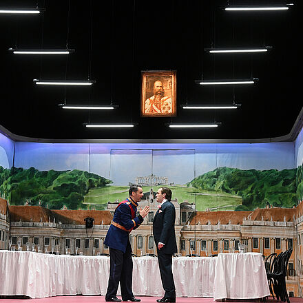 Zwei Männer stehen in der Mitte der Bühne, während links und rechts zwei Frauen aufmerksam zuhören.