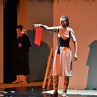 Hedda Gabler hält eine rote Scheibe empor