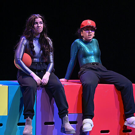 Auf der Treppe sitzen zwei Personen. Die eine trägt ein Cap, die andere hält einen Ball.