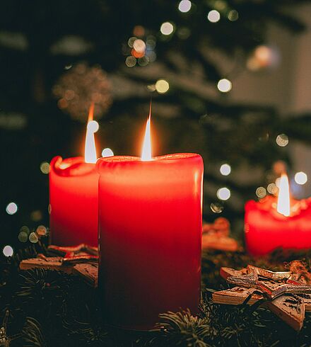Adventskranz mit roten brennenden Kerzen.