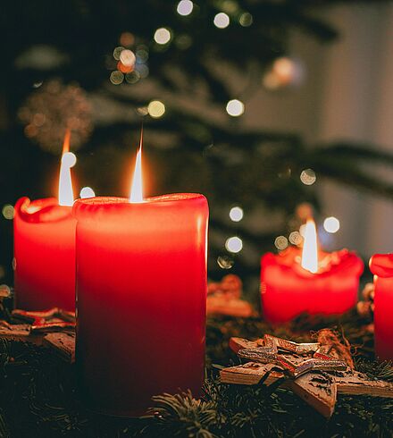 Adventskranz mit roten brennenden Kerzen.
