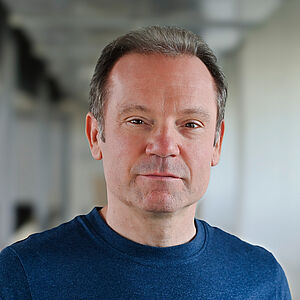 Portraitfoto von James Bobby. Er hat kurzes Haar und trägt einen blauen Pullover. Der Hintergrund ist verschwommen.