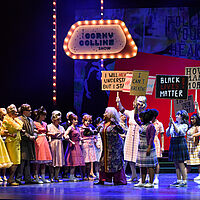 Motormouth Maybelle steht gemeinsam mit den Motormouth Kids, Tracy Turnblad und Edna Turnblad den Corny Collins Kids und deren Eltern gegenüber. Dabei halten sie Protestschilder unter anderem mit den Aufschriften „I can’t breathe“, „Black lives matter!“ und „We will not be silenced“. Die Gegenpartei hat ihre Arme miteinander verkeilt, sodass sie eine zweireihige Wand bilden.