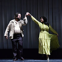 Werther, in Hemd und Cordjacke, und Charlotte, in grünem Kleid, tanzen und lächeln sich dabei an.