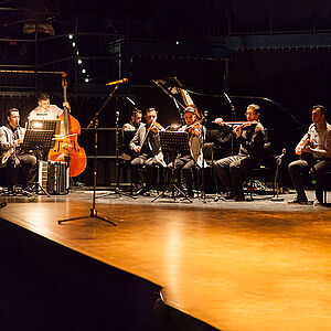 Das Dardo Balke Ensemble auf der Bühne. Es besteht aus sieben Männern an den Intrumenten Klarinette, kontrabass, Flügel, Violine und E-Gitarre.