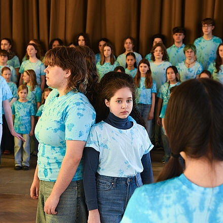 Auf dem Bild ist der Kinderchor zu sehen. Alle tragen ein blaues Oberteil.