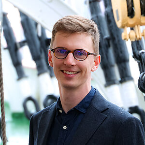 Portrait eines lächelnden jungen Mannes mit Brille