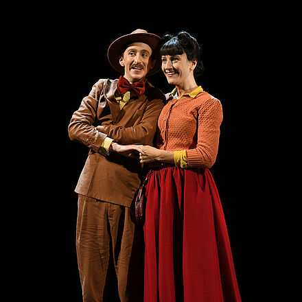 Ein Mann mit Hut und eine Frau umarmen sich.