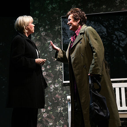 Zwei Frauen im Mantel sprechen energisch miteinander, hinter ihnen steht ein Mann