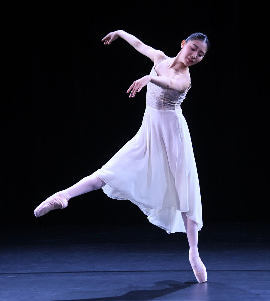 Eine junge Frau in einem weißen Kleid tanzt Ballett.