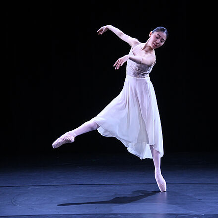 Eine junge Frau in einem weißen Kleid tanzt Ballett.