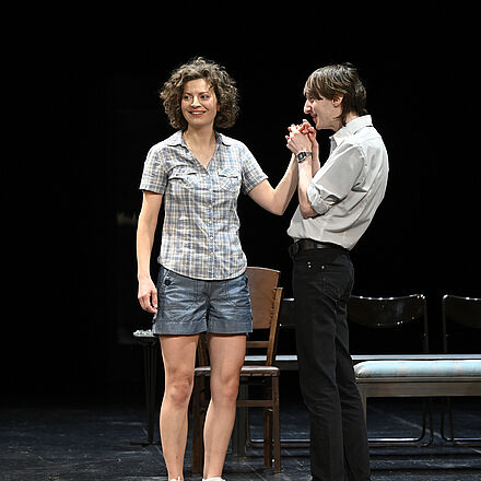 Eine Frau schaut verlegen nach links. Ein Mann hält ihre Hand.