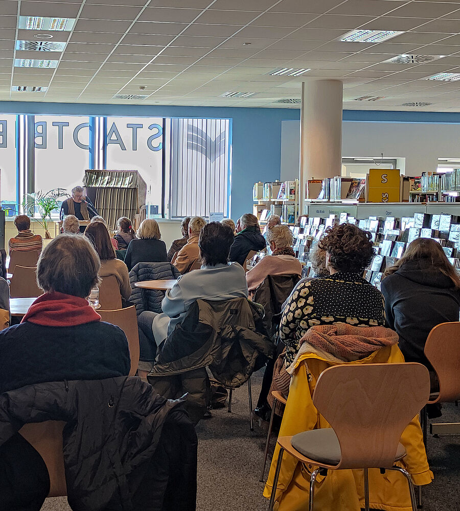 Menschen sitzen vor der Strandkorbbühne in der Stadtbibliothek