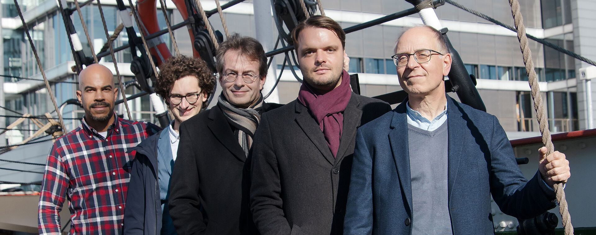 Orchester-Team des Stadttheaters Bremerhaven, bestehend aus fünf männlichen Personen. Sie stehen leicht hintereinander platziert auf einem Schiff.
