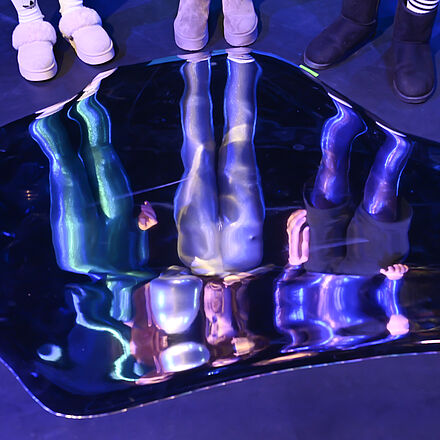 Auf dem Boden spiegeln sich die drei Personen.