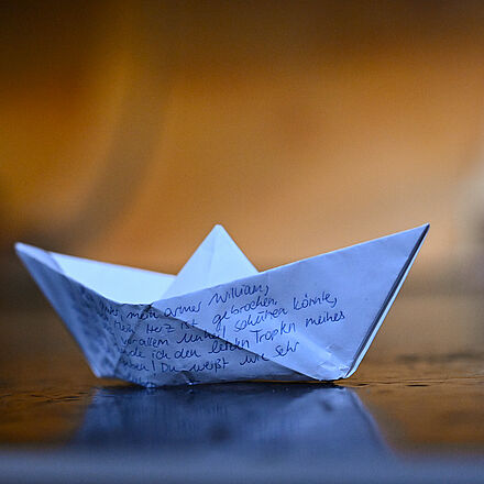 Ein Papierschiff, auf dem ein Brief geschrieben ist.