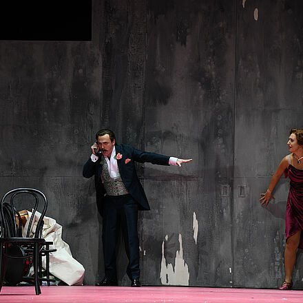 Ein Mann telefoniert, während eine Frau an der Wand steht.