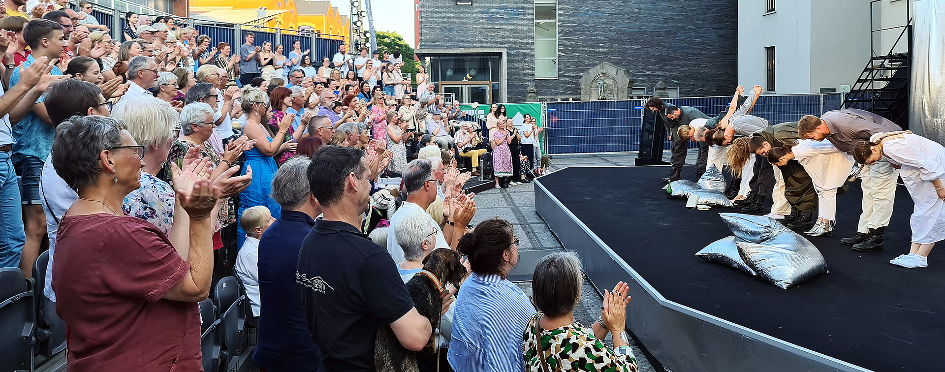 Applaudierendes Publikum vor dem sich verbeugenden Ensemble von "Cyrano de Bergerac" auf der Sommerbühne vor dem Stadttheater Bremerhaven.