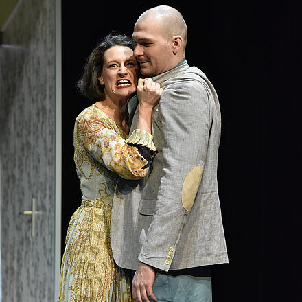 Dieselbe Frau steht neben einem anderen Mann und hält ihn am Kragen fest.