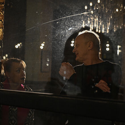 Die beiden Personen stehen am Fenster und schauen sich an.