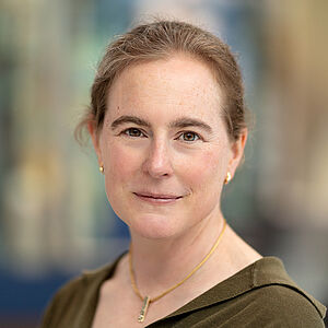 Portraitfoto von Franziska Grevesmühl-von Marcard. Sie trägt ihr rotblondes Haar zum Zopf. Sie ist in ein olivfarbenes Hemd gekleidet und trägt eine goldene Kette. 