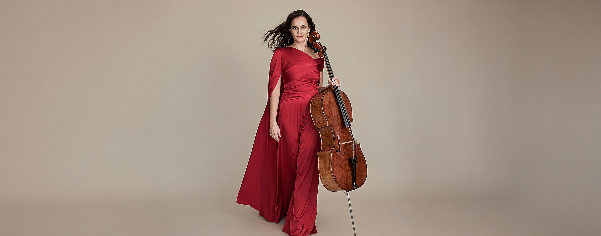 Foto von Raphaela Gromes. Sie hält eine Cello in ihrer Hand und sie trägt ein rotes Abendkleid.