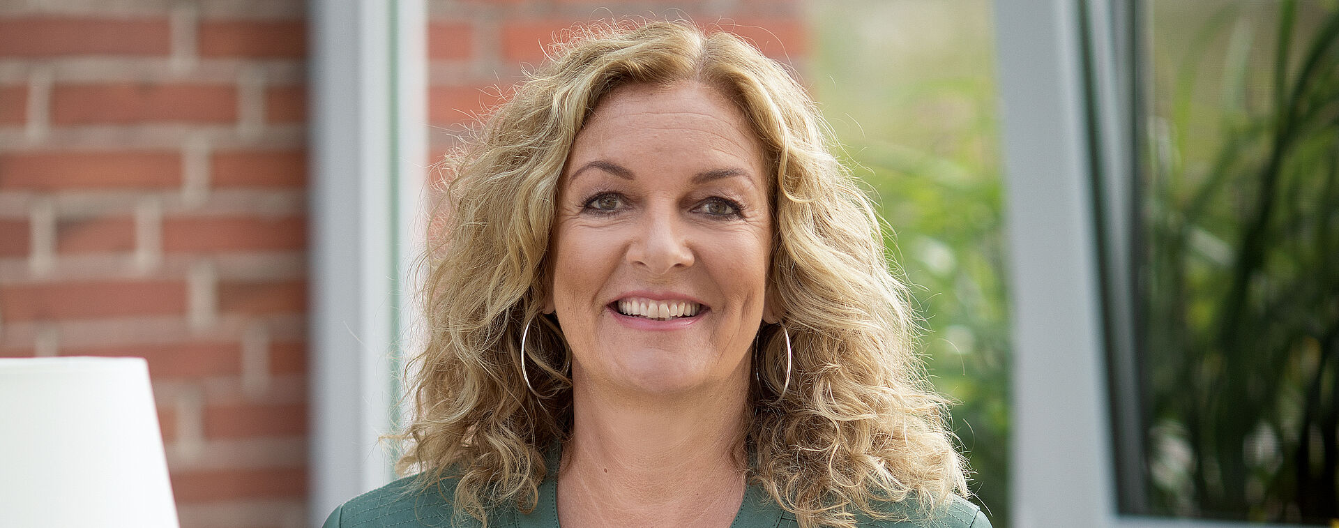 Portraitfoto von Bettina Tietjen. Sie hat blondes lockiges Haar und grinst.