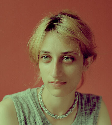 Portraitfoto von Lizzy Davis mit rotem Hintergrund.