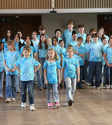 Der gesamte Kinderchor ist zu sehen. Alle tragen ein blaues Oberteil.