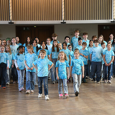 Der gesamte Kinderchor ist zu sehen. Alle tragen ein blaues Oberteil.