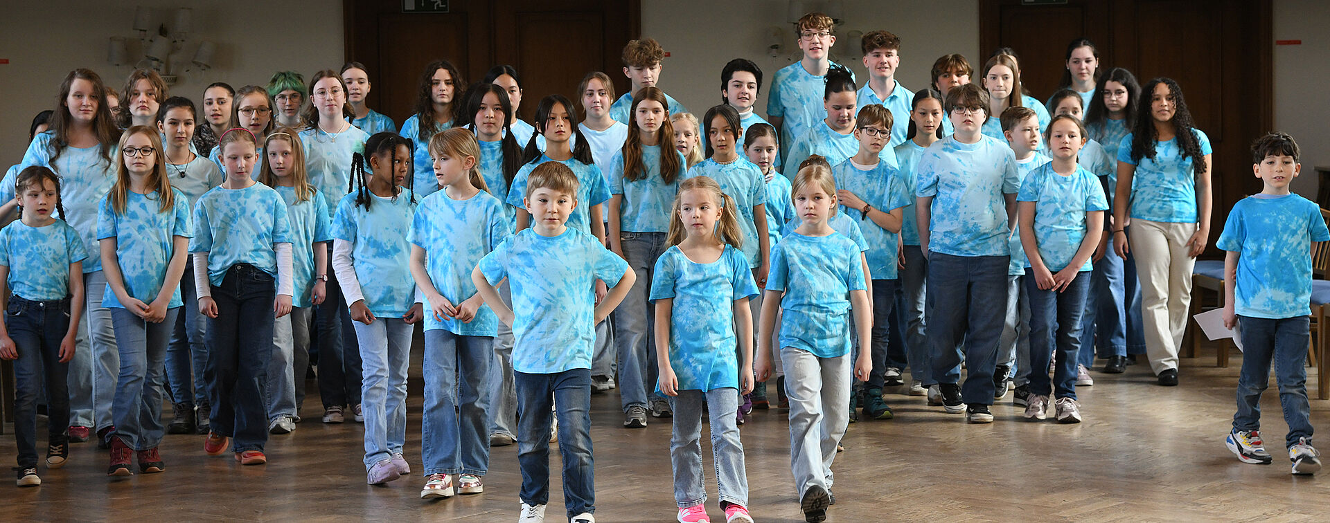 Der gesamte Kinderchor ist zu sehen. Alle tragen ein blaues Oberteil.