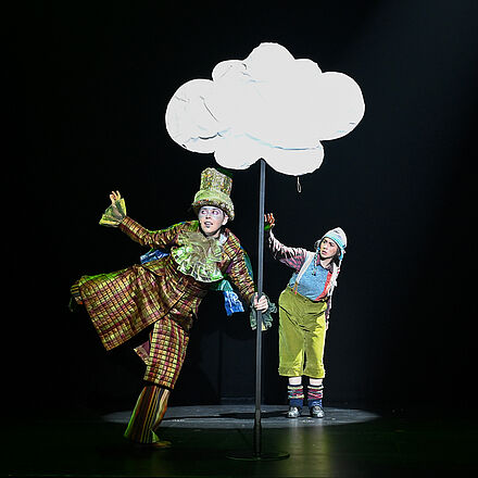 Ein Wettertroll turnt an einer Wolke. Die kleine Person schaut fragend zu