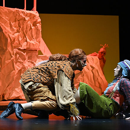 Der Fuchs steht gefährlich nah bei der kleinen Person, die verängstigt schaut. Im Hintergrund versteckt sich eine Gans