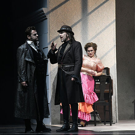 Zwei Männer unterhalten sich. Eine Frau steht dahinter und schaut skeptisch.